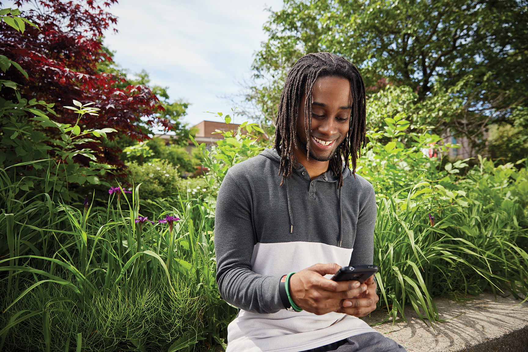 Student texting in a sunny garden