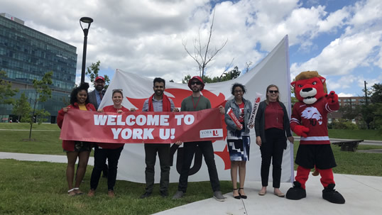 A group of people holding a 'Welcome to York U' banner, with Yeo