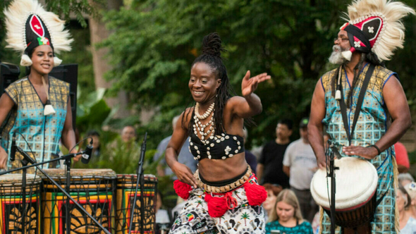 Black woman seen dancing alongside African drummers