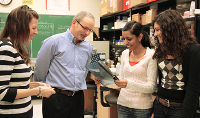 Professor teaching students, while students gather around.