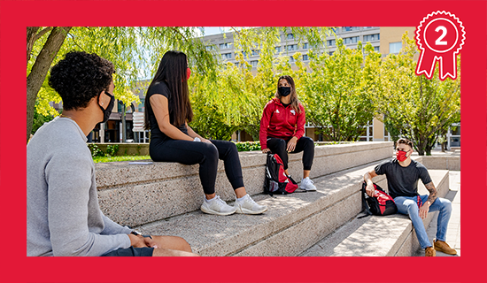 Students wearing masks, sitting on steps in the Commons.