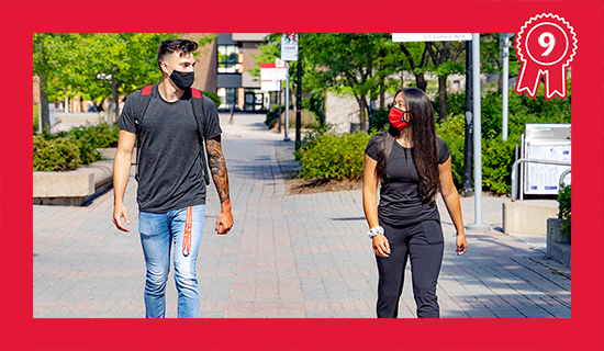 Two students wearing non-medical reusable face masks walk across campus.