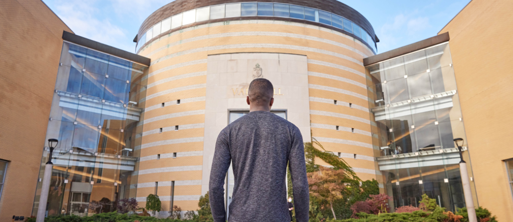 Young man standing in front of Vari Hall with their back to the camera