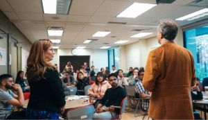 two professors speaking to a group of students in a classroom