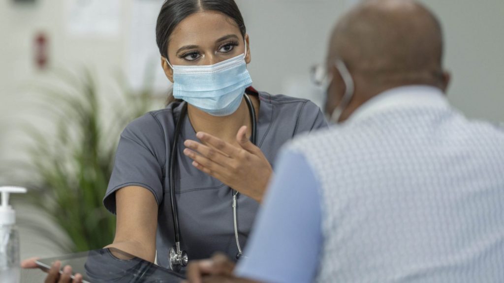 A nurse talking with a patient and showing information on an iPad