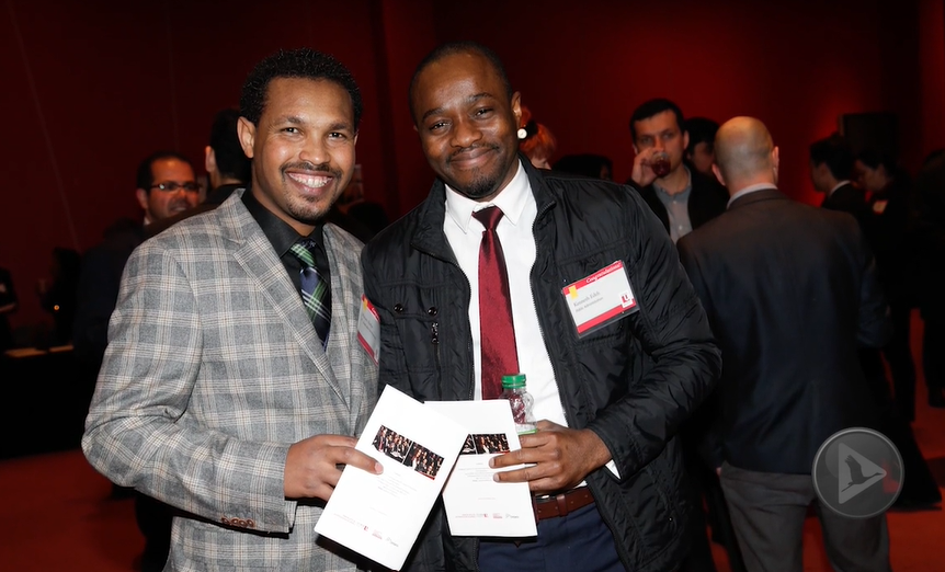 Two men posing for a picture with other people in the background