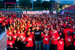 A large crowd of people in red t-shirts are standing at a stadium. 