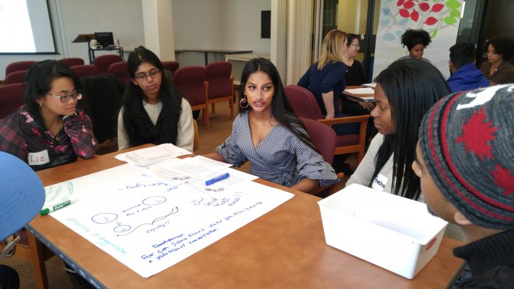 Five students sitting at a table and having a discussion.