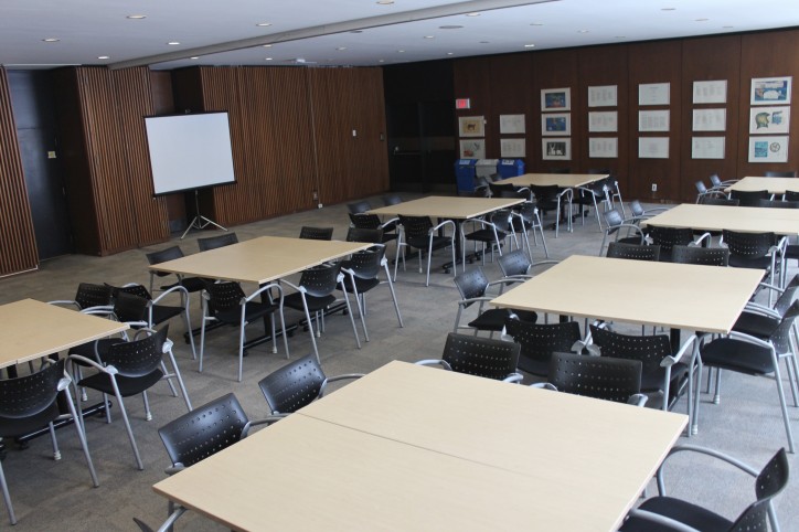 A meeting room set up with square tables and chairs.