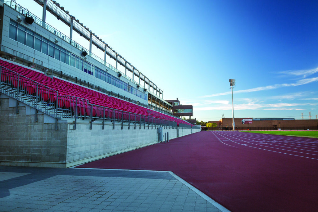 A stadium with empty seats overlooking a playing field and track.