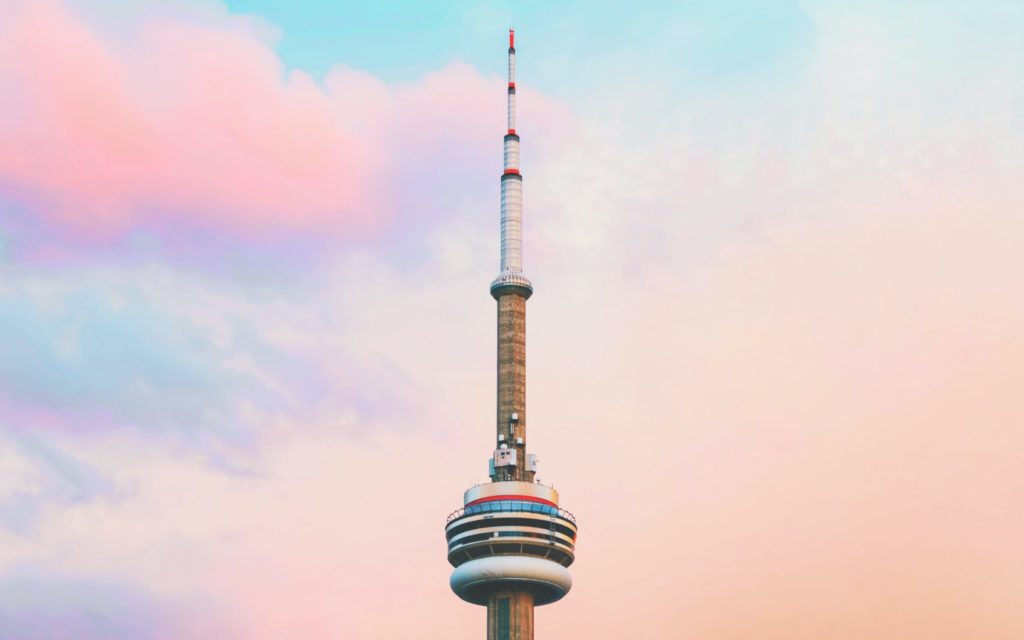 Peak of CN tower in front of pink and blue sky