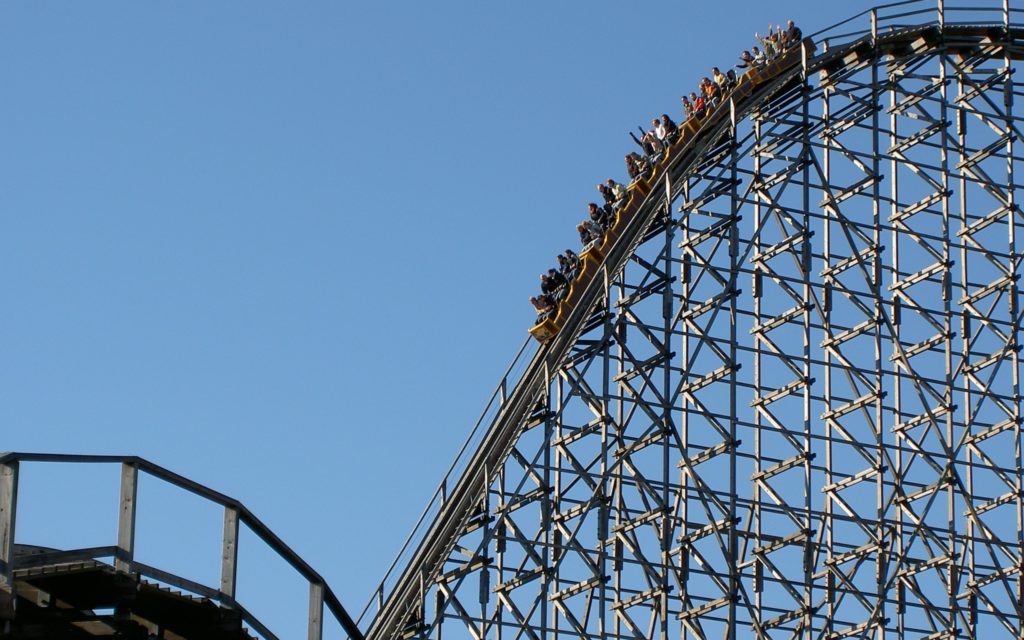 Passengers ride rollercoaster in front of blue sky