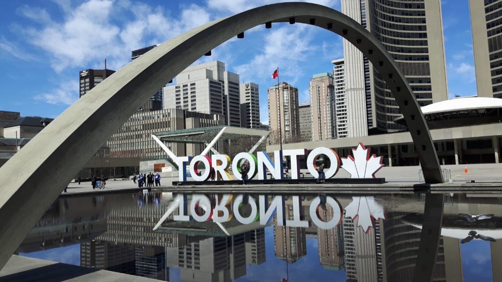 Toronto sign amid concrete buildings and structures against blue sky