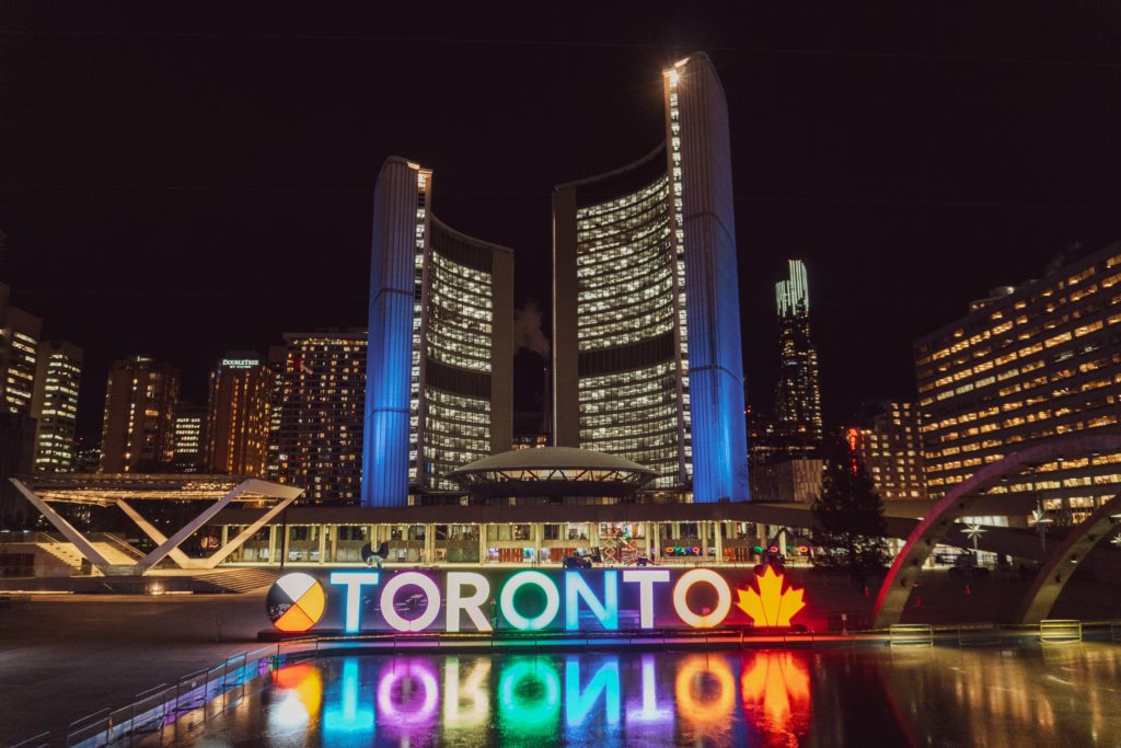 Brightly-lit Toronto sign near water fountain at night