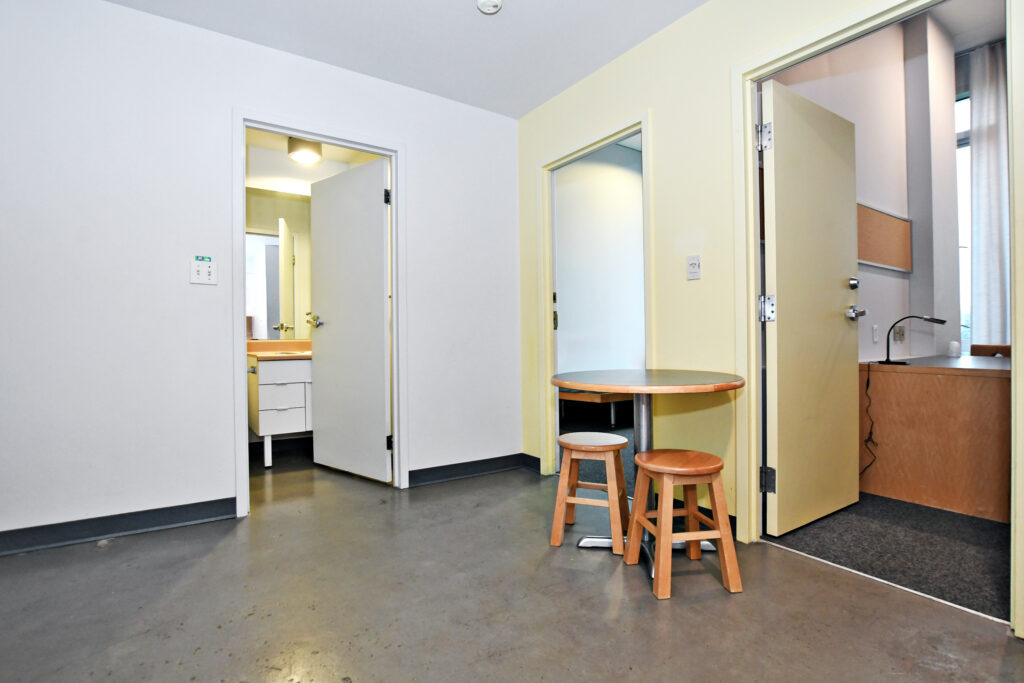 View from Pond Road Residence kitchenette showing dining table with 2 stools and entrances to washroom, 2 separate bedrooms.