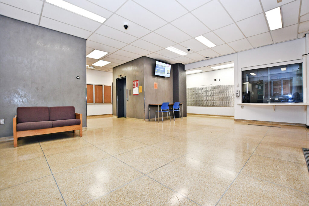 Lobby of Bethune Residence. A large space showing an elevator, mailboxes, a table with chairs, and a small seating area.