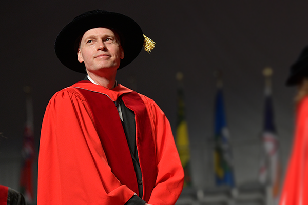 Man standing on stage in PhD regalia