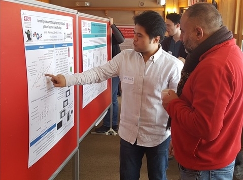 Person points at a poster in a conference. Another person is present, looking at the poster.