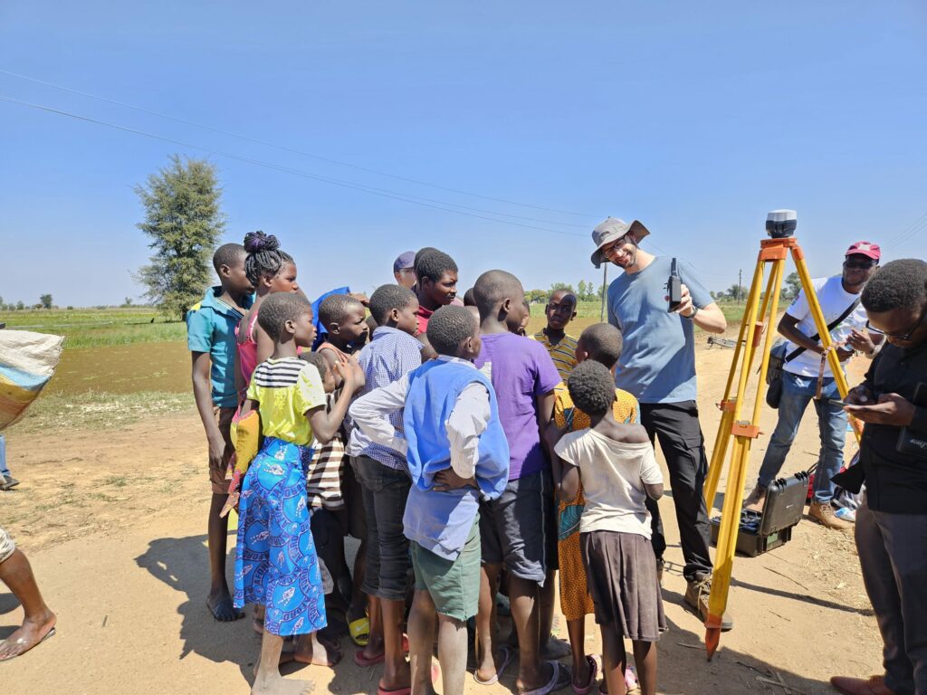 Villagers watch their village as seen from the drone