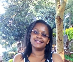 image of Esther Munene, the academic administrator of The BHER Learning Centre in Dadaab standing outside under a tree.