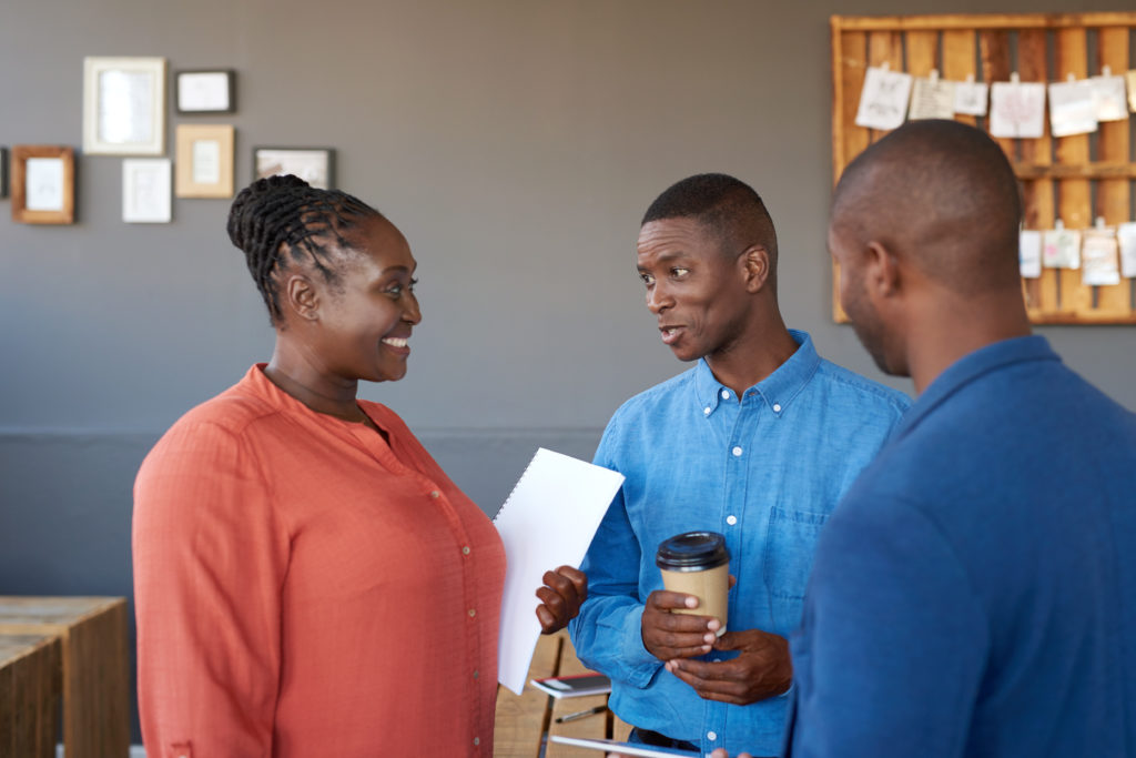 Black woman and 2 Black men from a charity standing and talking 