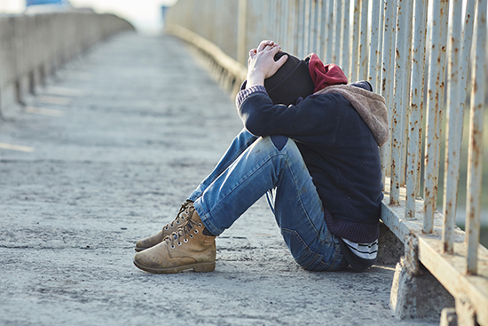 Young homeless boy sitting on a bridge