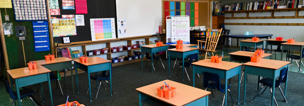 An empty elementary school classroom with desks and chairs