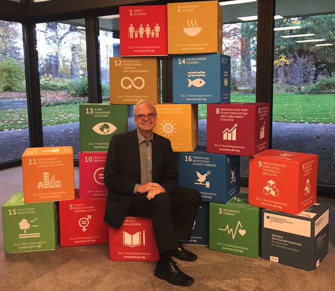 York University UNESCO Chair Charles Hopkins sitting in front of a background of blocks that each represent 1 of the United Nations’ 17 Sustainable Development Goals