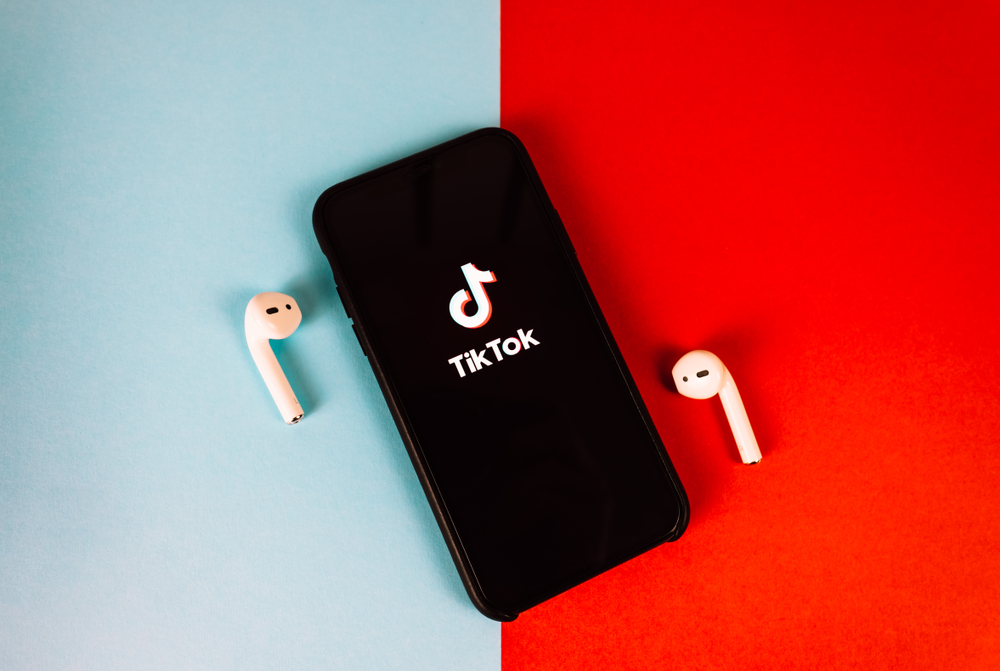iPhone with TikTok app logo on the screen. red-blue background