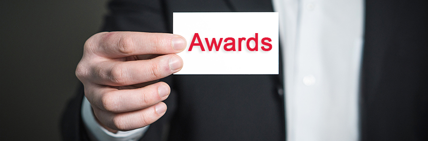 white male hand holding a small sign that reads "Awards"