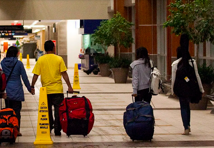 A family walking in an airport with luggage in hand