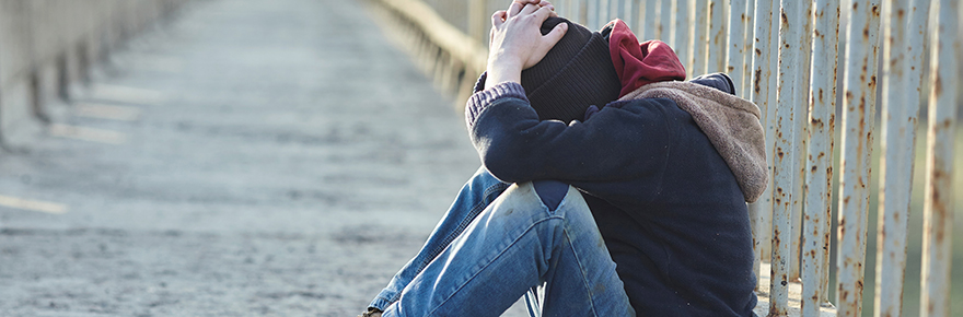 young homeless man sitting on a bridge