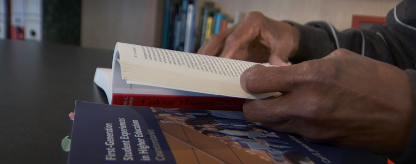 Hands of Professor Carl James turning the pages of one of his books