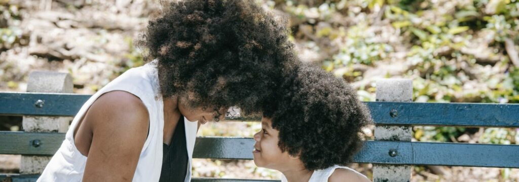 Black woman and child sitting outside on bench 