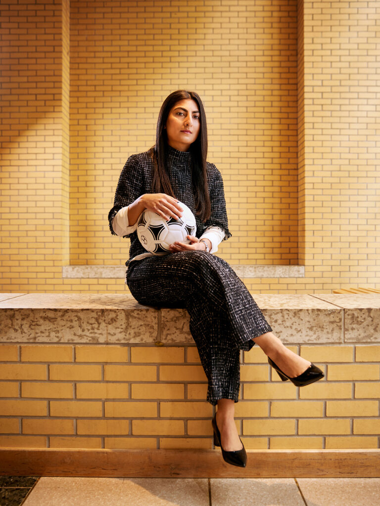 Farkhunda Muhtaj sitting on a ledge in Vari Hall (York University) with a soccer ball on he lap