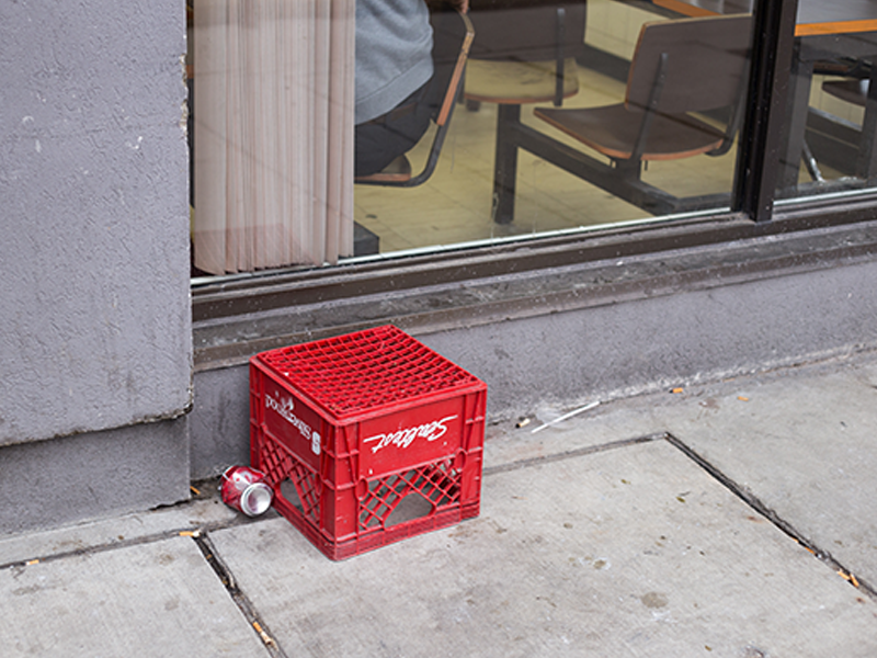 Upside down milk crate with an empty pop can beside it on a Toronto Street

