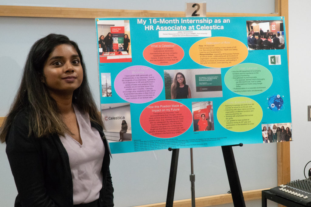 A poster presenter standing beside her poster on her internship at Celestica.