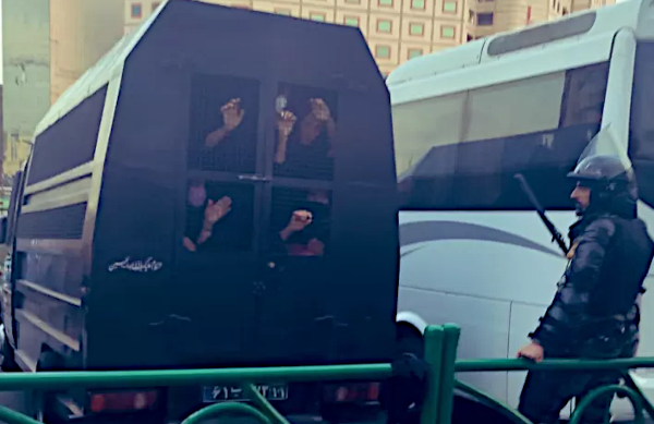 A police standing besides a cage with people captured inside