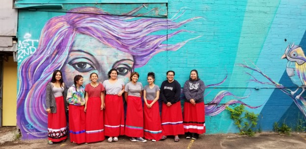 Young Indigenous Women standing in front of a picture wall