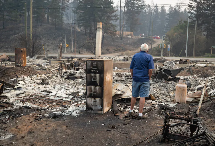 A man looks over the remains of his onetime house after it was destroyed by the White Rock Lake wildfire in Monte Lake, east of Kamloops, B.C., in August 2021. He sold the house a few years earlier and its new occupants escaped the fire. THE CANADIAN PRESS/ Darryl Dyck