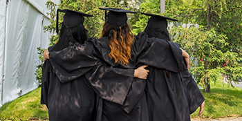 3 student in graduation gown taken from behind