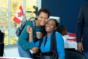 Two females pose for the camera while one holds a Canadian flag