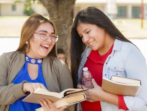 Two girls holding books and talking