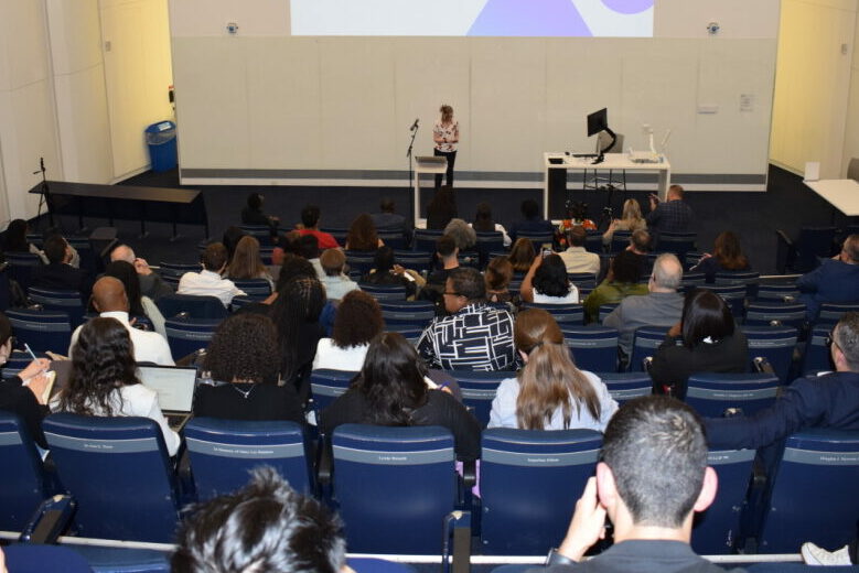 Une étudiante s'adressant à son exposé devant un large public dans une salle de conférence, engageant et éclairant les auditeurs.