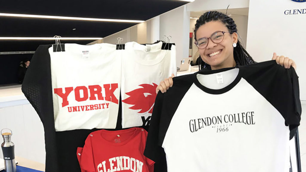 student holding up a shirt with the Glendon logo