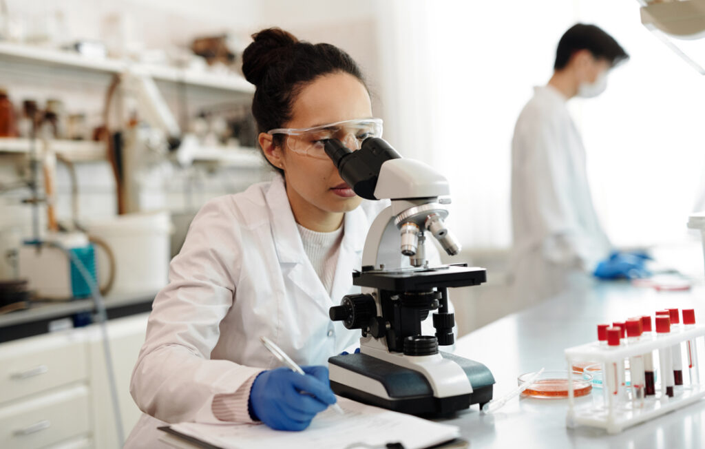 Female Scientist in White Lab Coat Using a Microscope
