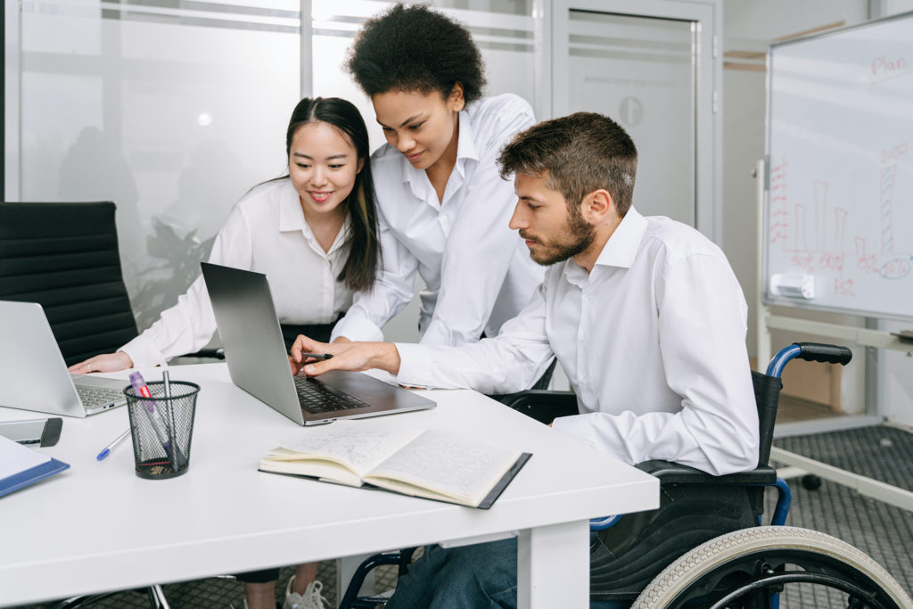 photo of three people looking at a couple of laptops