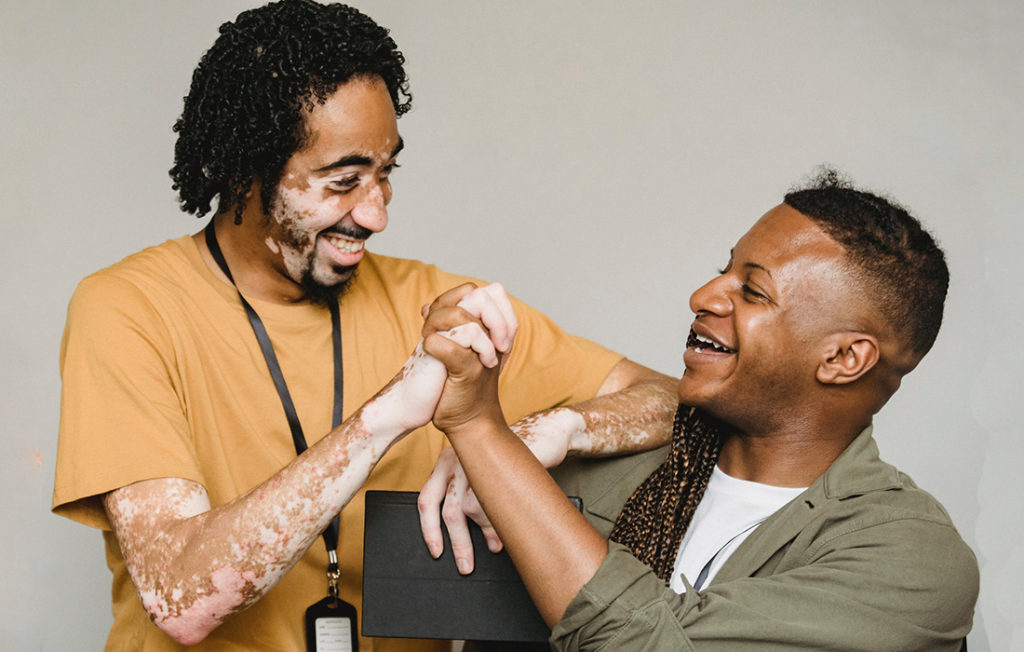 photo of two men smiling and clasping hands