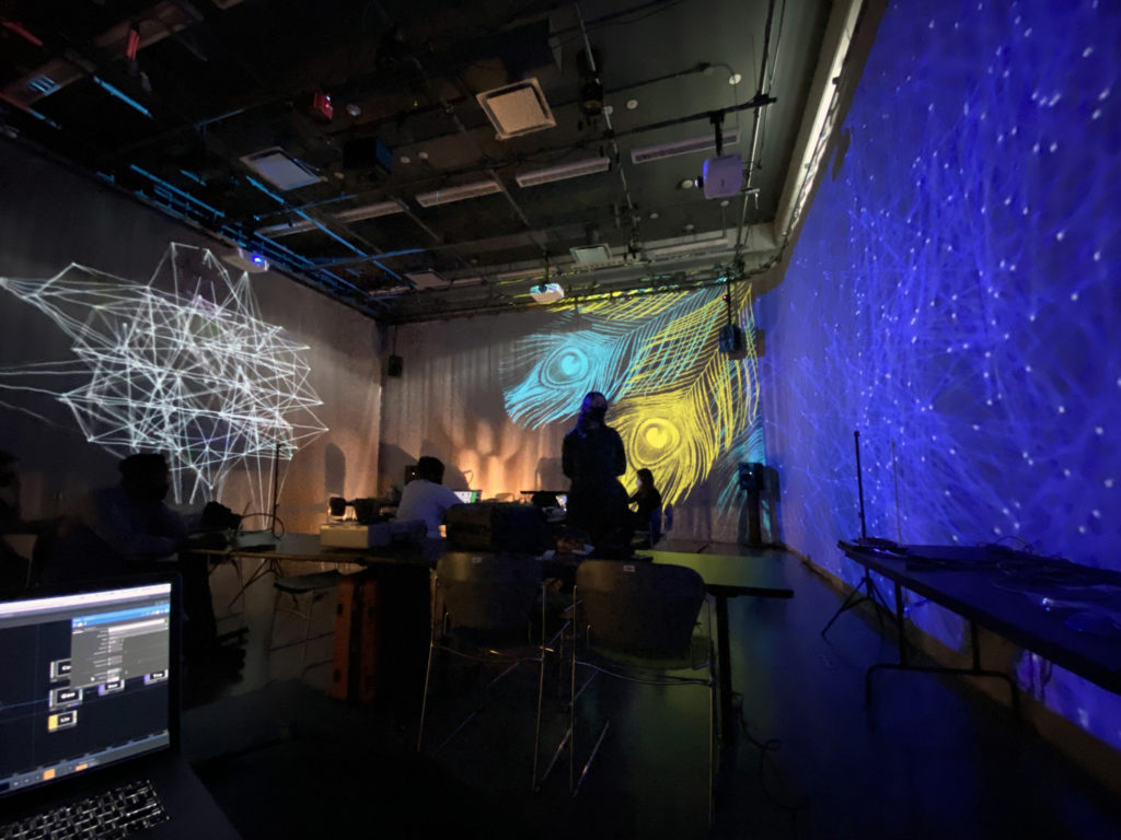 image of students in a room surrounded by different projections on the wall