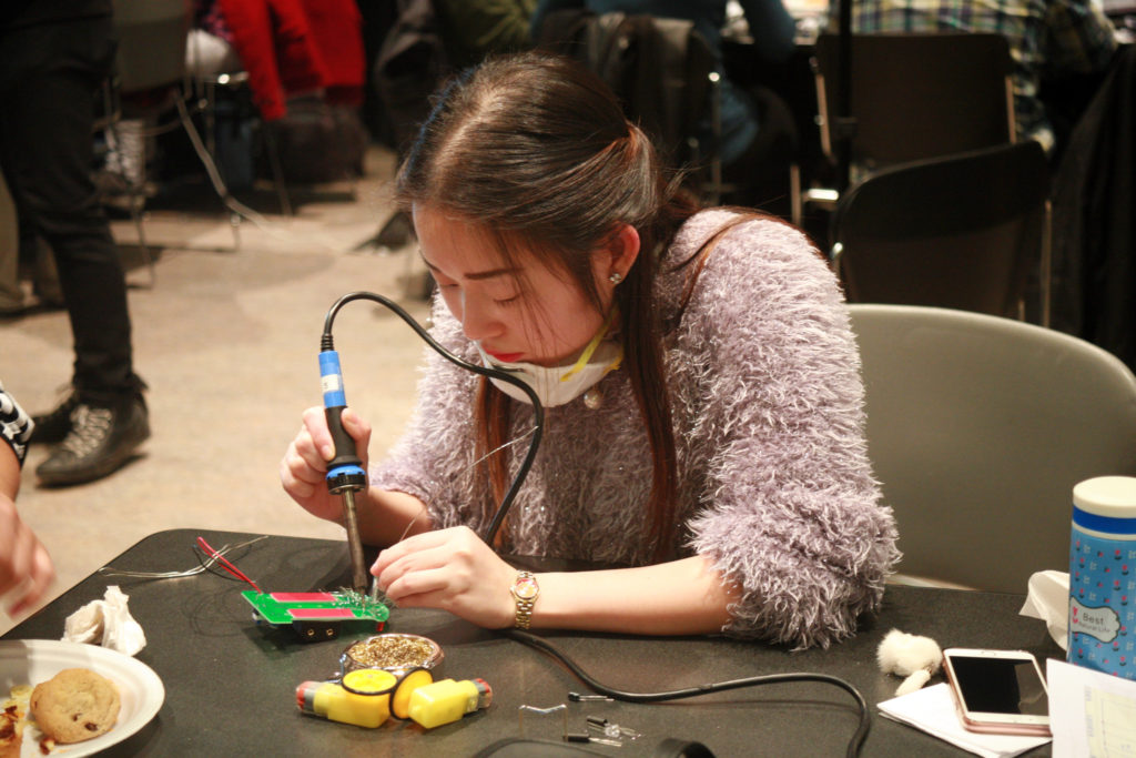 photo of a young woman soldering on a circuit board